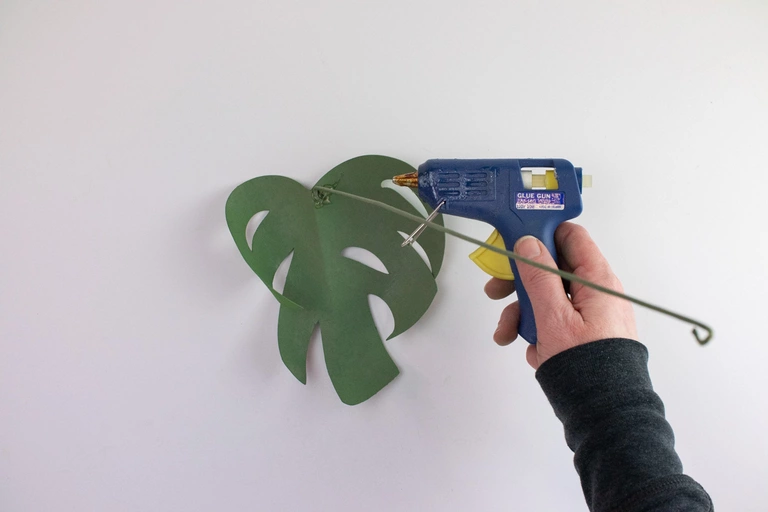 Attaching a monstera leaf to a wire stem using hot glue.